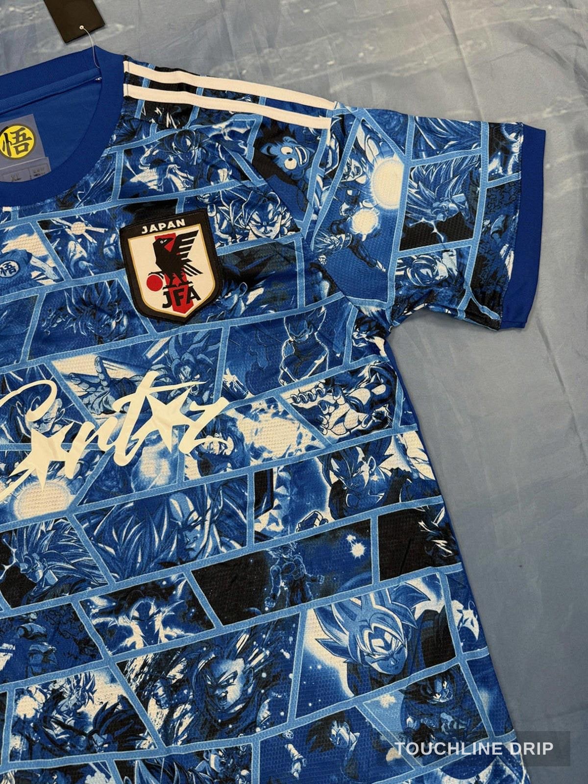 badge closeup product image of Adidas x Corteiz Japan Anime Fusion Light Blue Concept Jersey